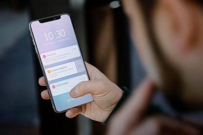 Image of a man holding a phone displaying screen notifications