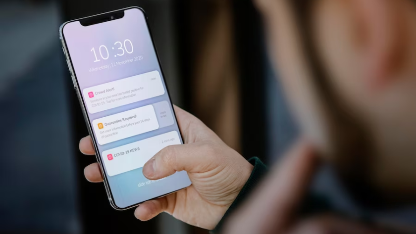 Image of a man holding a phone displaying screen notifications